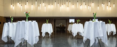 Foyer mit Pendelleuchten und Stehtischen